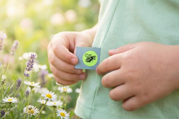 Etichetta azzurra con ape cucita nella cucitura di una maglia per bambini